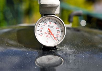 A thermometer on top of a grill. 