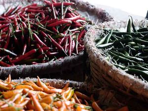 Three large baskets with filled small red, green, and orange hot chiles.