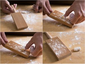 A hand rolling gnocchi on a gnocchi paddle. 