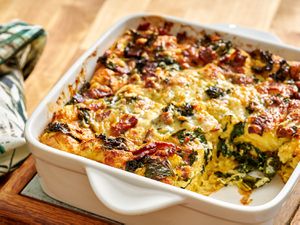 Kale and bacon strata in a baking dish with one portion removed