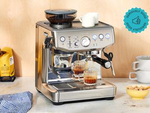 A Breville espresso machine brewing coffee into a small cup.