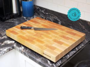 A wooden cutting board with a knife on top of it on a kitchen countertop.