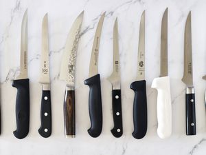 A selection of boning knives on a marble countertop