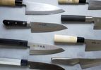 a variety of deba knives on a pale grey concrete surface