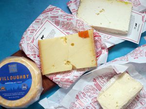 Murray's cheese box with four cheese on their wrapping on a blue surface