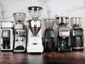 Six espresso grinders lined up against a marble backdrop