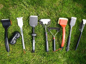 multiple grill brushes on a grassy surface