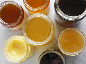 a variety of jars of honey with their tops open