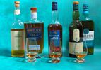 multiple bottles of whisky and whisky tasting glasses on a blue surface