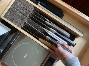 a hand pulling a knife out of a cork-lined drawer insert