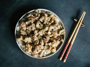 Overhead view of Steamed Pork Ribs on a plate of rice placed next to a pair of chopsticks.