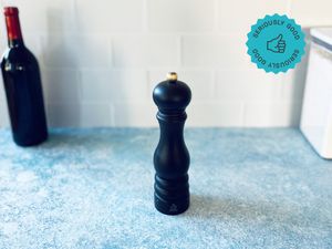 the peugeot pepper mill on a blue surface with white tile backdrop