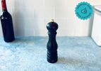 the peugeot pepper mill on a blue surface with white tile backdrop