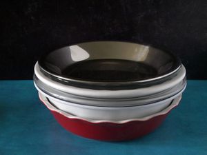 pie pans stacked together on a blue countertop with black backdrop