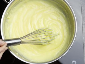 Making pastry cream in a saucier with a hand mid-whisk.