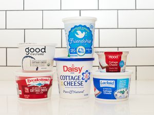 Six brands of cottage cheese stacked atop a counter.