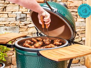 A Big Green Egg kamado smoker loaded with chicken wings.