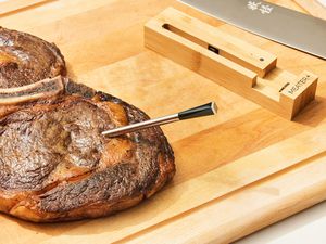 The Meater Plus Smart Meat Thermometer with Bluetooth stuck into a piece of lamb displayed on a cutting board