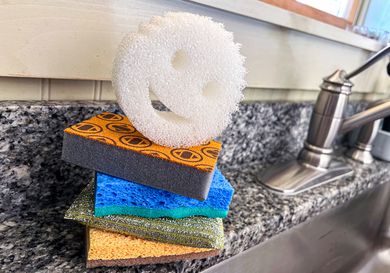 A stack of dishwashing sponges next to a kitchen sink.