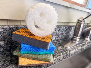 A stack of dishwashing sponges next to a kitchen sink.