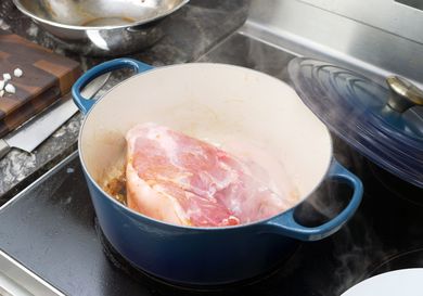 the le creuset dutch oven with a piece of pork shoulder searing in it. 