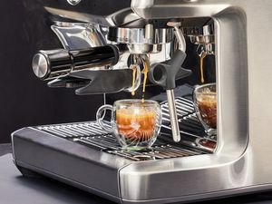 Close up of the Breville Barista Express Impress brewing an espresso into a glass cup 