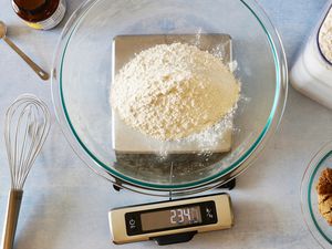 A glass bowl with flour on it set on a kitchen scale that has a pull-out screen.