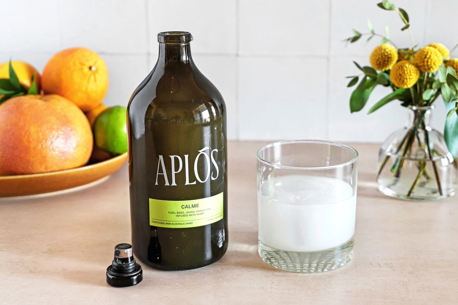 A bottle of Aplos beside a glass filled with the non-alcoholic drink.