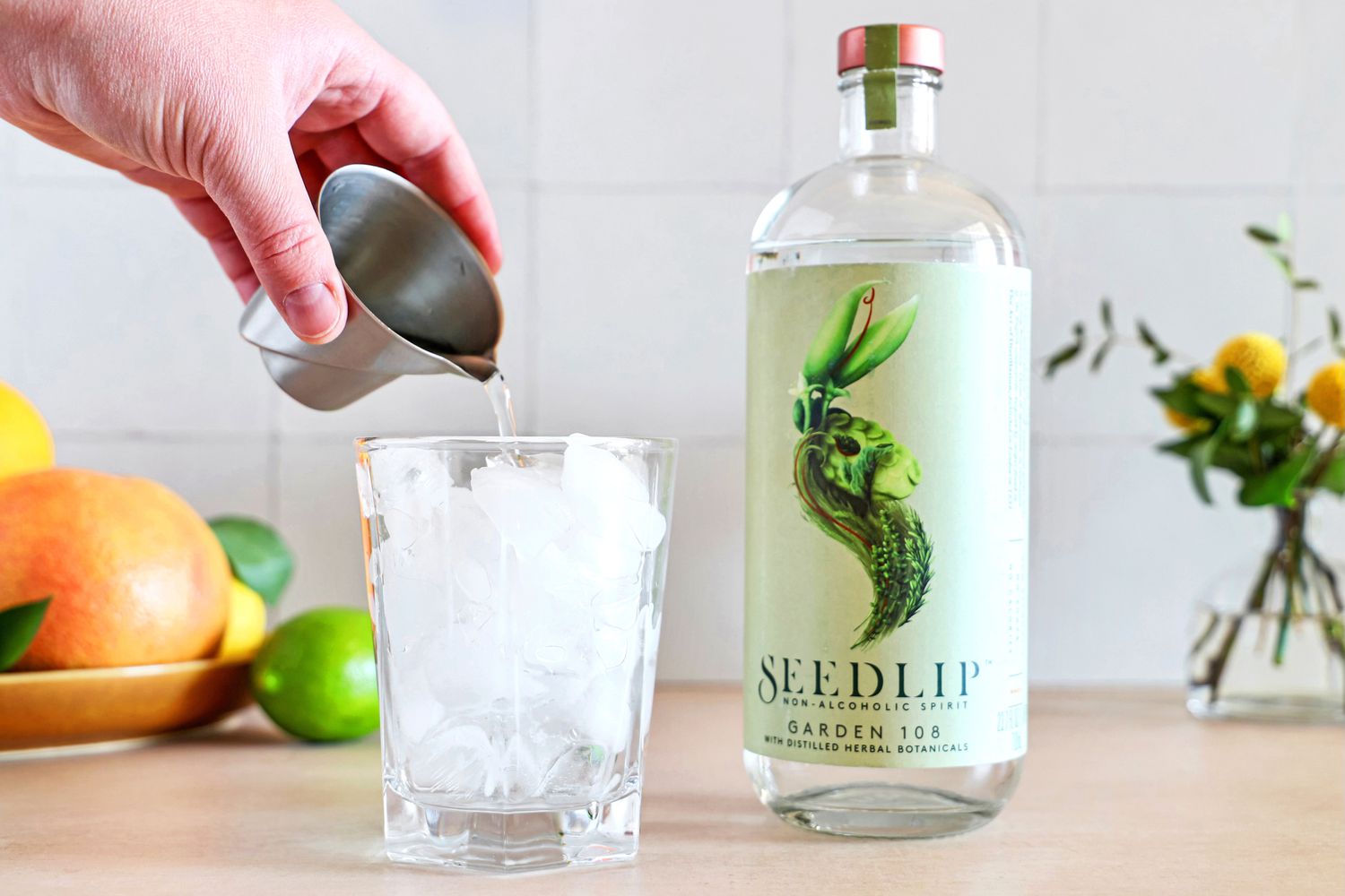 A person pouring some of the Seedlip non-alcoholic spirit into a glass with ice.