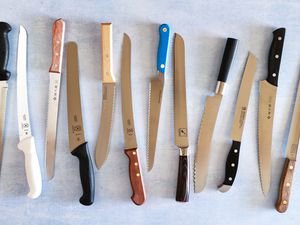 Group of serrated bread knives displayed on a blue surface