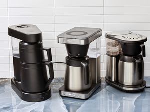 Three coffee makers on a blue kitchen countertop.