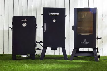 three electric smokers side by side on a lawn