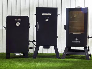 three electric smokers side by side on a lawn