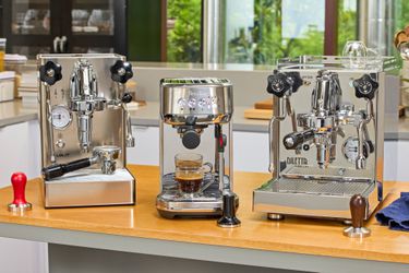 Three espresso machines on a kitchen countertop.