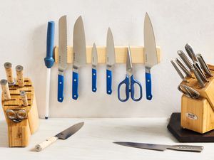 Two knife blocks and one magnetic knife strip set on a marble countertop and white wall.