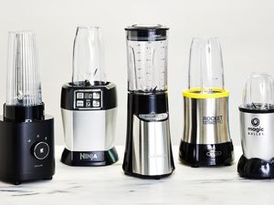 Five personal blenders on a marble kitchen countertop.