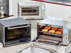 three toaster ovens on a countertop with one opened with toast inside