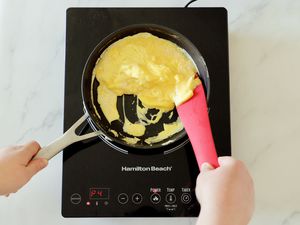 cooking scrambled eggs in a pan on an induction burner