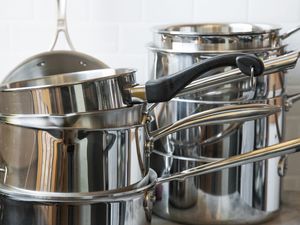 two stacks of stainless steel saucepans on a kitchen countertop