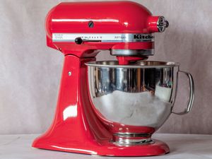 a red stand mixer on a marble surface