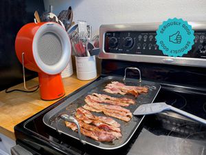 the airhood next to a griddle of bacon on the stove