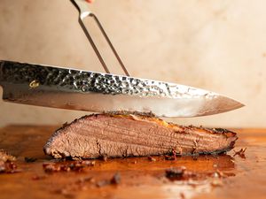 A person slicing meat using a carving knife and fork.