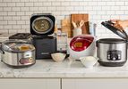 Four rice cookers on a kitchen countertop.