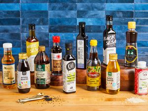 a variety of sesame oils on a wooden surface with a blue tile background