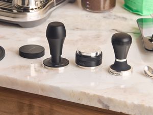 Three espresso tampers on a marble kitchen countertop.