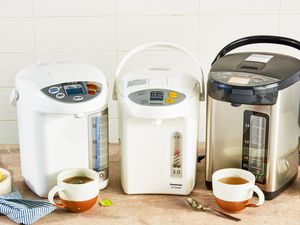 Three hot water dispensers on a wooden countertop.