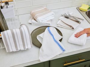 Numerous kitchen towels on a kitchen countertop.