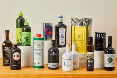 Numerous bottles of olive oil on a wooden countertop.