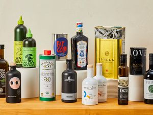 Numerous bottles of olive oil on a wooden countertop.