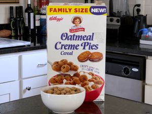 Box of Kellogg's Little Debbie Oatmeal Creme Pies cereal on a counter with a bowl of cereal in front of box